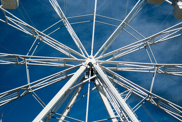Naklejka premium white ferris wheel against blue sky and clouds