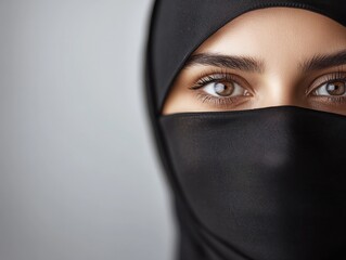 Naklejka premium Close-up portrait of a woman in a black hijab, showcasing expressive brown eyes and an aura of mystery and elegance.