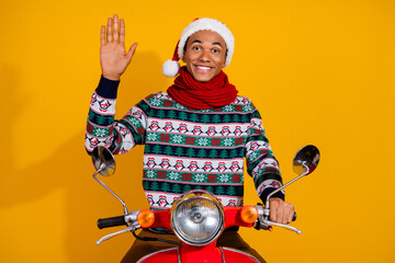 Photo of nice young man ride scooter arm wave hi you wear sweater christmas festive time isolated on yellow color background © deagreez