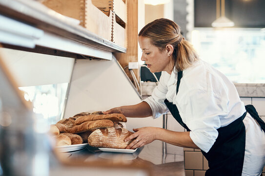 Bakery, busy and woman with bread in cafe for serving food, products and pastry for small business. Restaurant, coffee shop and person for service, help and baked goods for hospitality in store