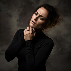 A woman in a thoughtful pose, clasping her hands near her chin, expressing concern or contemplation.