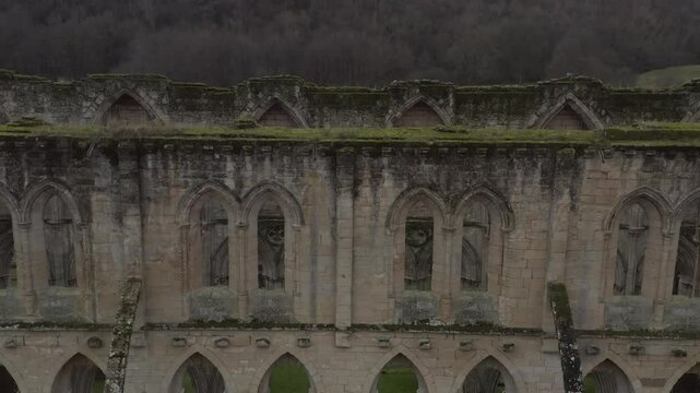 Drone shot rising over the ancient ruins of Rievaulx Abbey's architectural details and surroundings in North Yorkshire, England