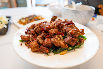 fried sticky ribs marinated in soy sauce and ginger sprinkled on white dish on marble table, chineese style.