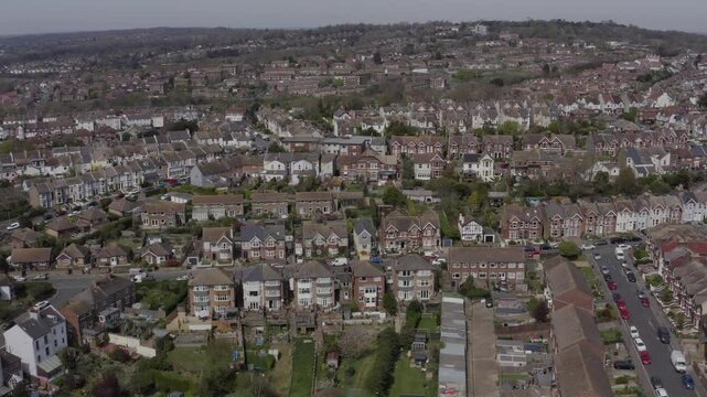 Aerial tracking along residential neighborhood in Hastings with rows of houses and tree-lined streets in England, UK