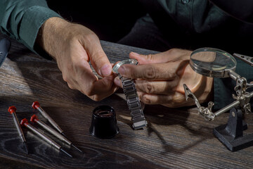 Watchmaker repairing watches looking through magnifying glass monocular. Professional senior watch fixer in repair services workshop.