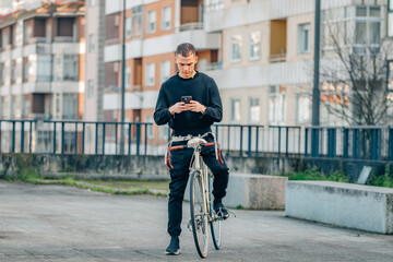 Obraz premium urban young man with mobile phone on top of the bicycle in the street