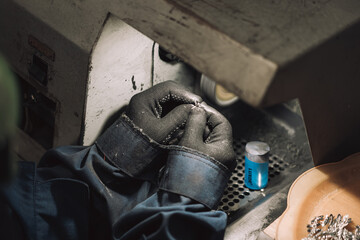 Lapidary worker polishing boulder precious stone or metal. no face, unrecognizable person.