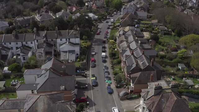Drone shot of suburban residential street in Hastings with cars parked alongside houses on a clear day in England, UK