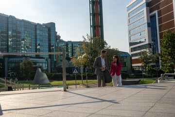 Obraz premium Business people, walking and travel in city with discussion on morning commute, partnership and happy. Employees, man and woman with conversation, collaboration and networking outdoor in urban town 