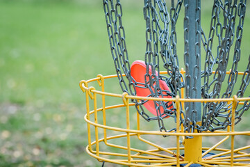 pink disc hitting the chains of discgolf basket