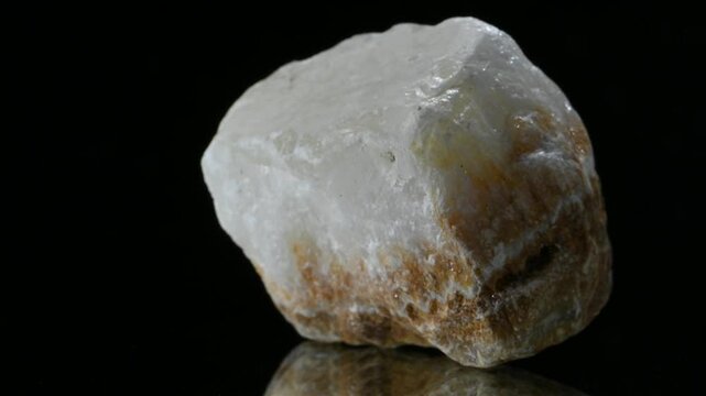 Alabaster (form of gypsum - hydrous sulfate of calcium) mineral sample rotation slowly against a black background.