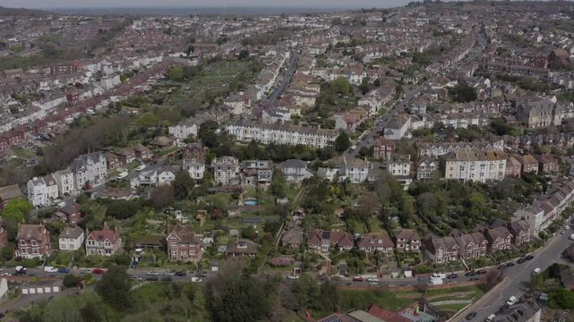 Wide tracking aerial shot of hilly residential streets, gardens and greenery in Hastings, England