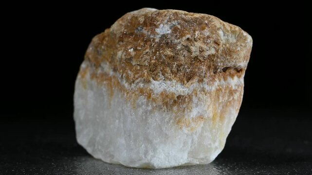 Alabaster (form of gypsum - hydrous sulfate of calcium) mineral sample rotation slowly against a black background.
