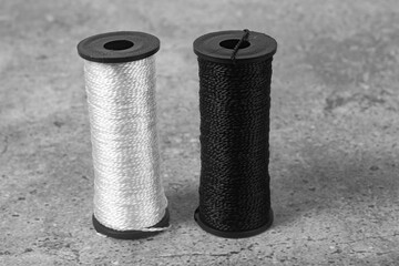 Close-up of two rolls of black and white nylon thread.