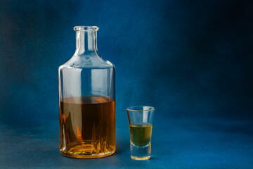 Bottle of whiskey and glass on blue background.