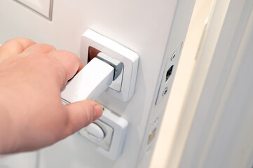 A woman's hand in close-up opening a white modern bathroom door