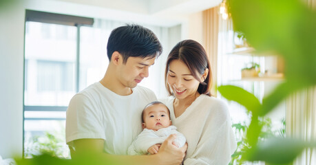 Obraz premium Young Asian family with infant in bright living room, white background