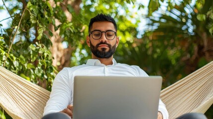 Businessman relaxing on a hammock with a laptop on his knees, worklife balance, digital nomad lifestyle