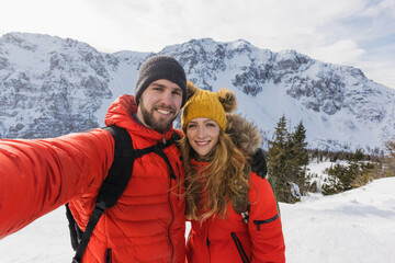Climbing couple takes a selfie from a snowy landscape in the winter mountains