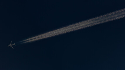 Airplane in the blue sky with white clouds and contrail.