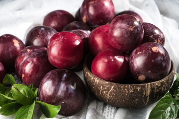 Obraz premium Juicy Summer Plums: Fresh Red and Black Plums on a Rustic Wooden Background