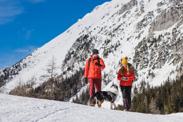 Couple enjoys a day outdoors hiking a snowy mountain with their dog in winter