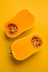 Butternut squash halves on vibrant yellow background, highlighting pumpkin seeds and their health benefits