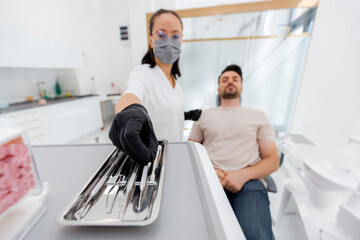 Dentist prepares tools while patient relaxes in a bright modern dental clinic setting