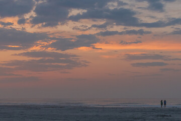 Avalon, New Jersey - Peaceful Sunrise at this beach on the New Jersey shore with two silhouettes of people watching the sun come out of the Atlantic Ocean