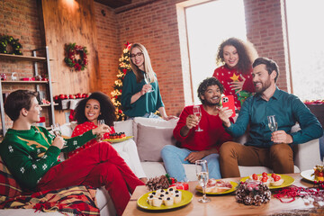 Photo of cheerful young people friends group sit couch enjoy celebrate cozy christmas party decor spacious apartment indoors