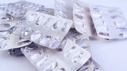 Many empty blisters of pills on a white fabric background, close-up, top view, health, medications, antidepressants, addiction, drugs, vitamins, antibiotics, garbage recycling