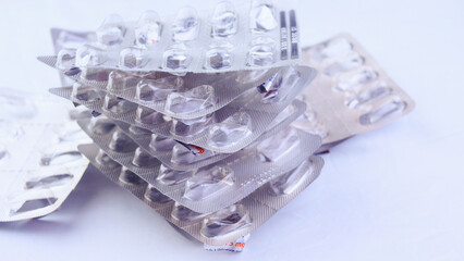 Many empty blisters of pills on a white fabric background, close-up, top view, health, medications, antidepressants, addiction, drugs, vitamins, antibiotics, garbage recycling