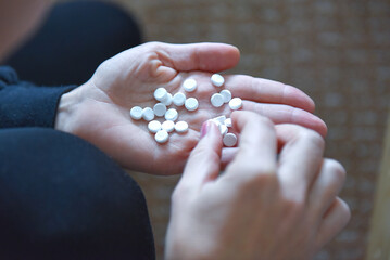 A woman holds several tablets in her hand