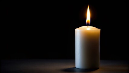Burning white candle on black background