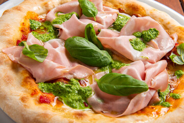 Primo piano di una deliziosa pizza condita con mortadella e pesto di basilico, cibo italiano 