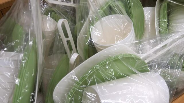 Lots of new disposable tableware close-up - plastic cups, plates and other plastic tableware in bags.