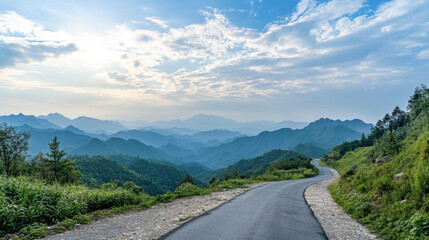 Naklejka premium Scenic road curving through lush green mountains under a cloudy sky