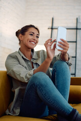 Young happy woman text messaging on cell phone at home.
