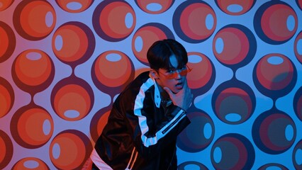 Caucasian dancer in causal shirt perform break dancing while standing at party stage. Professional hipster looking at camera while moving hand and stretch arm to lively and freestyle song. Regalement.