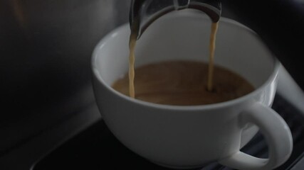 Closeup of footage of a coffee machine pouring coffee to a white mug