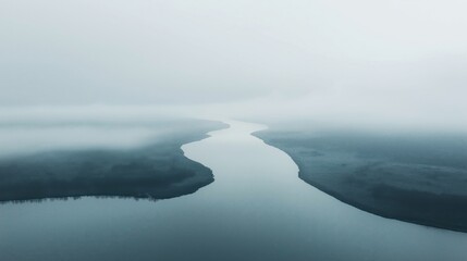 Obraz premium A tranquil river winding through a foggy landscape, surrounded by soft mist and calm waters.