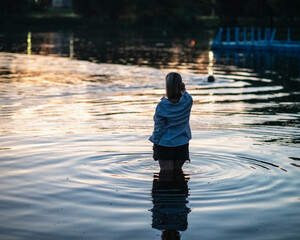 Portrait of a young beautiful blonde girl on the river on a summer evening.