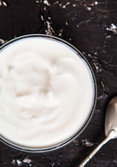 Bowl of tasty fresh sour cream on a dark background