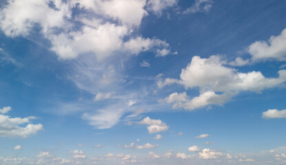 A beautiful view of the sky with fluffy white clouds scattered across a bright blue background, creating a serene and peaceful atmosphere.