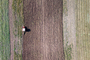 Fototapeta premium Aerial view of a tractor plowing the fields, showcasing agricultural activity and the patterns created on the soil.