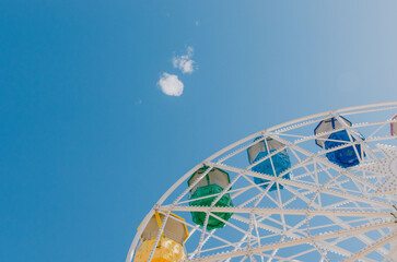 Colourful Ferris wheel set against a bright blue sky with soft clouds on a sunny day at Tibidabo in Barcelona