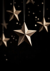 Obraz premium Star-shaped cardboard decorations hang against a black background in a close-up view.Minimal creative Christmas holiday concept.Copy space,flat lay