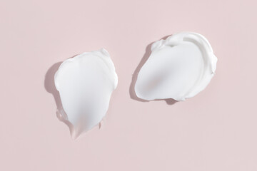 White beauty cream smear smudge on pink background. Cosmetic skincare product texture. Face cream, body lotion swipe swatch