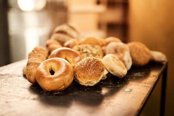Rolls, bakery and table with bread for wheat, food or pastry production at warehouse or factory. Closeup, baking and mix with ingredients or fresh produce on counter for breakfast, dough or heast