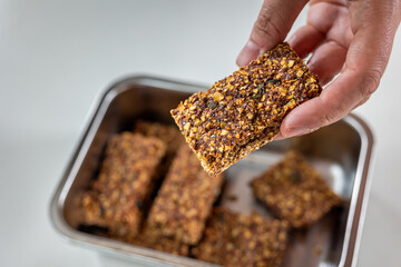 holding muesli bar in the hand with more in the container in background